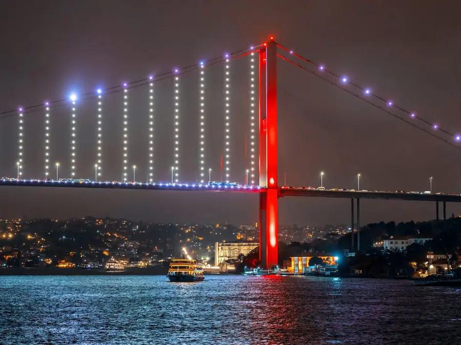 Gece ışıklandırılmış Boğaz Köprüsü ve İstanbul kıyısı